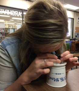 Katie Krueger examines marks on an antique mug using a jeweler's lupe with 8x magnification.